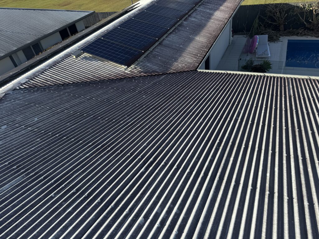 Dark staining across a corrugated roof beside solar panels and a pool in Mount Pleasant