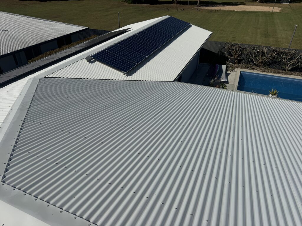 The same light-grey corrugated roof after cleaning, with solar panels and the pool visible
