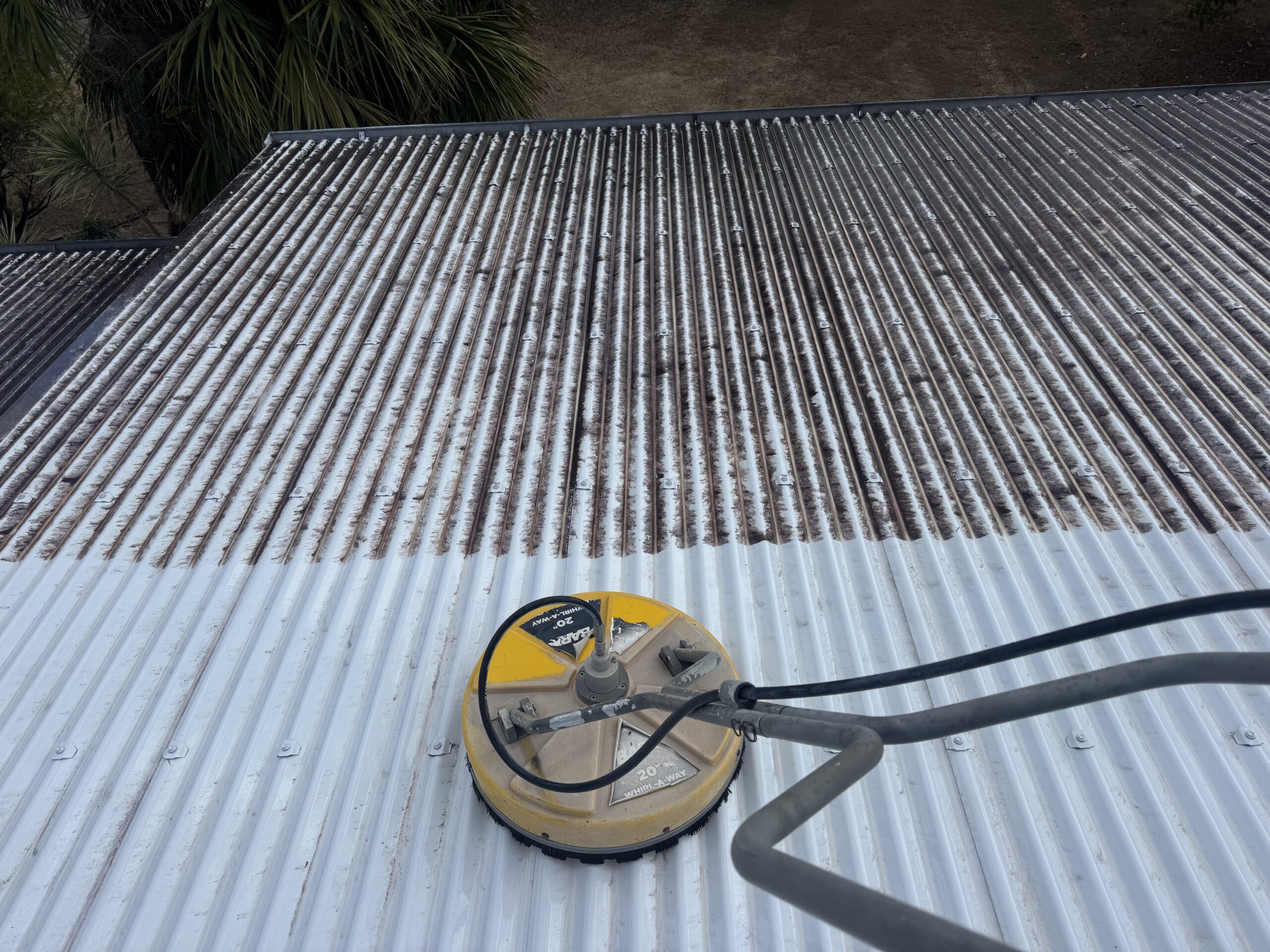 Whirlaway surface cleaner beside a clear cleaning line on the Calen metal roof