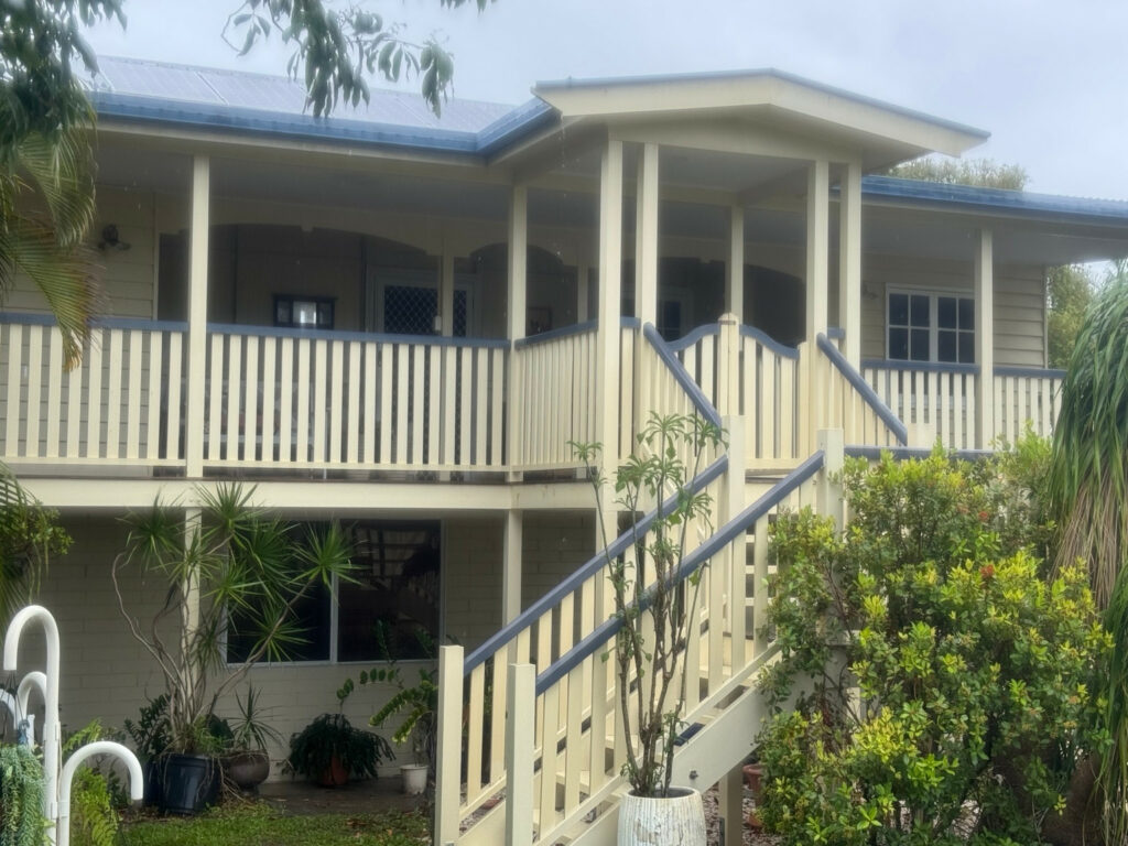 Cream weatherboard house with a front verandah and stairs at the East Mackay soft-washing project