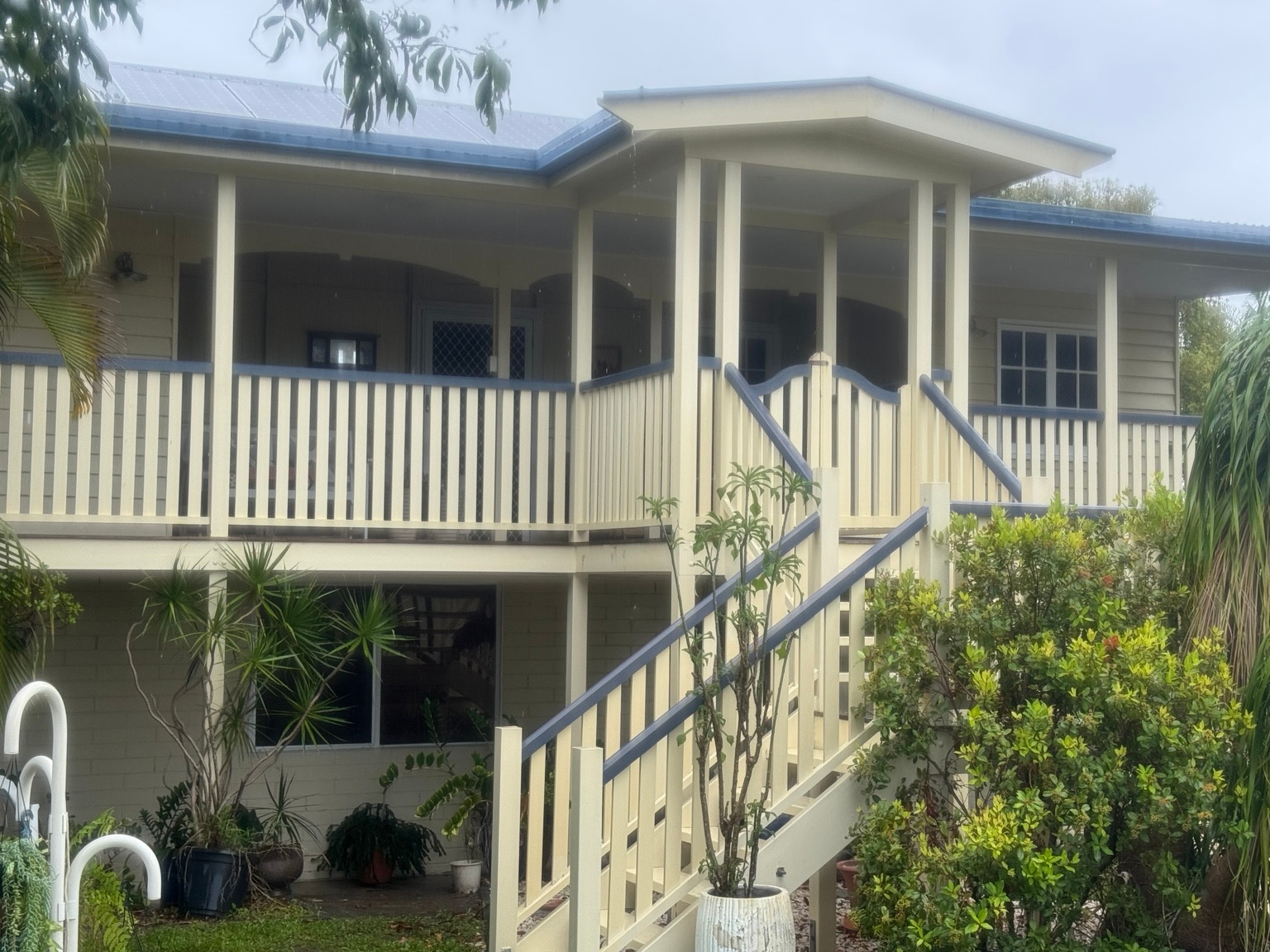 Cream weatherboard house with a front verandah and stairs at the East Mackay soft-washing project