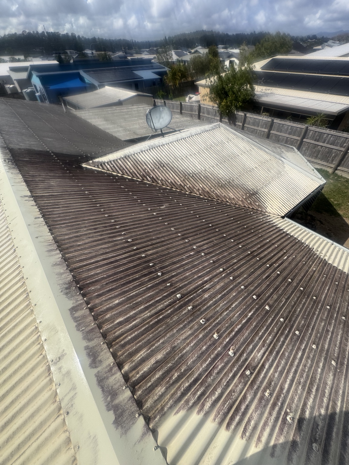 Dark surface build-up on adjoining metal roof sections near a satellite dish
