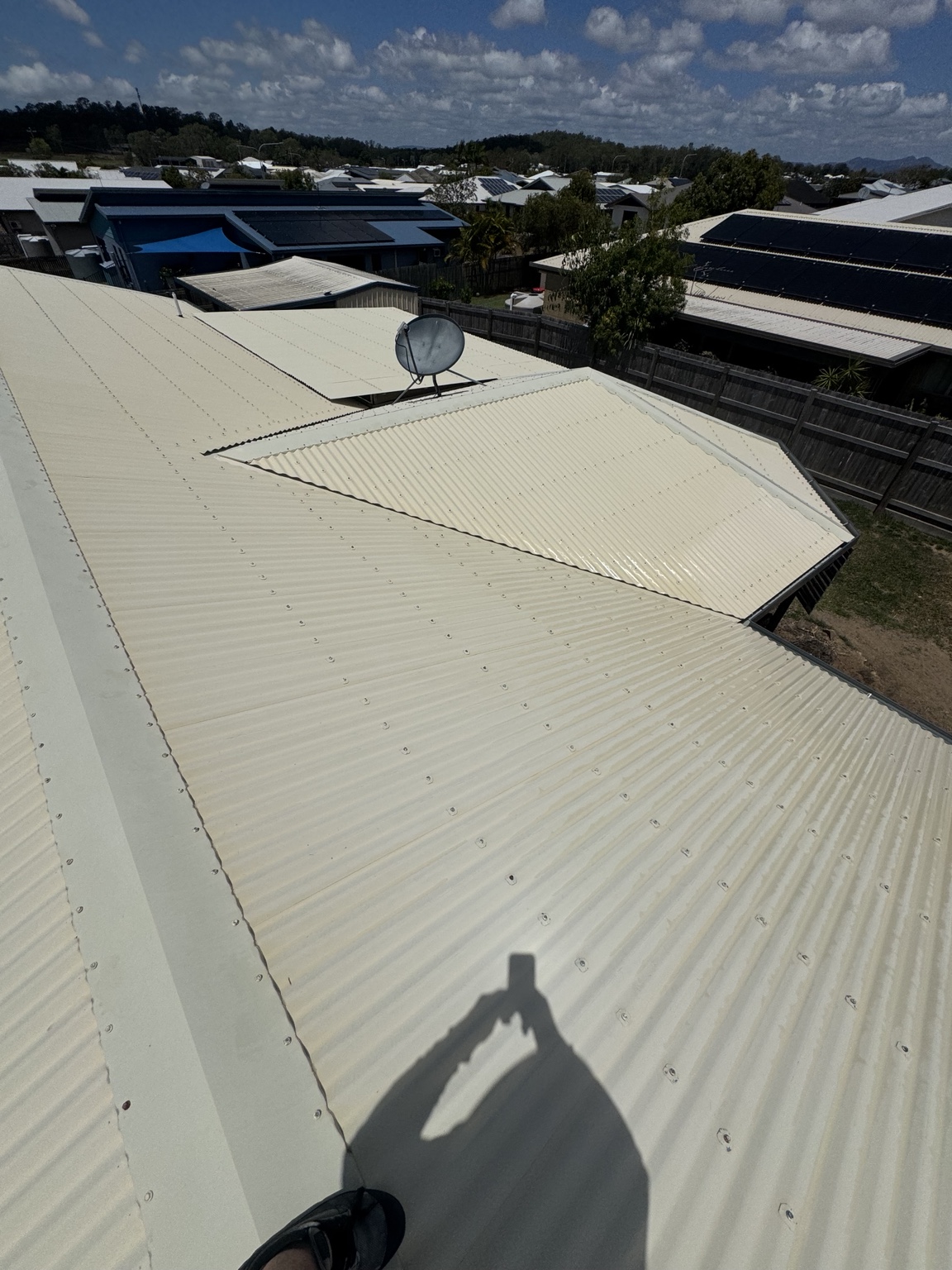 Clean light-coloured metal roof sections around a satellite dish after washing